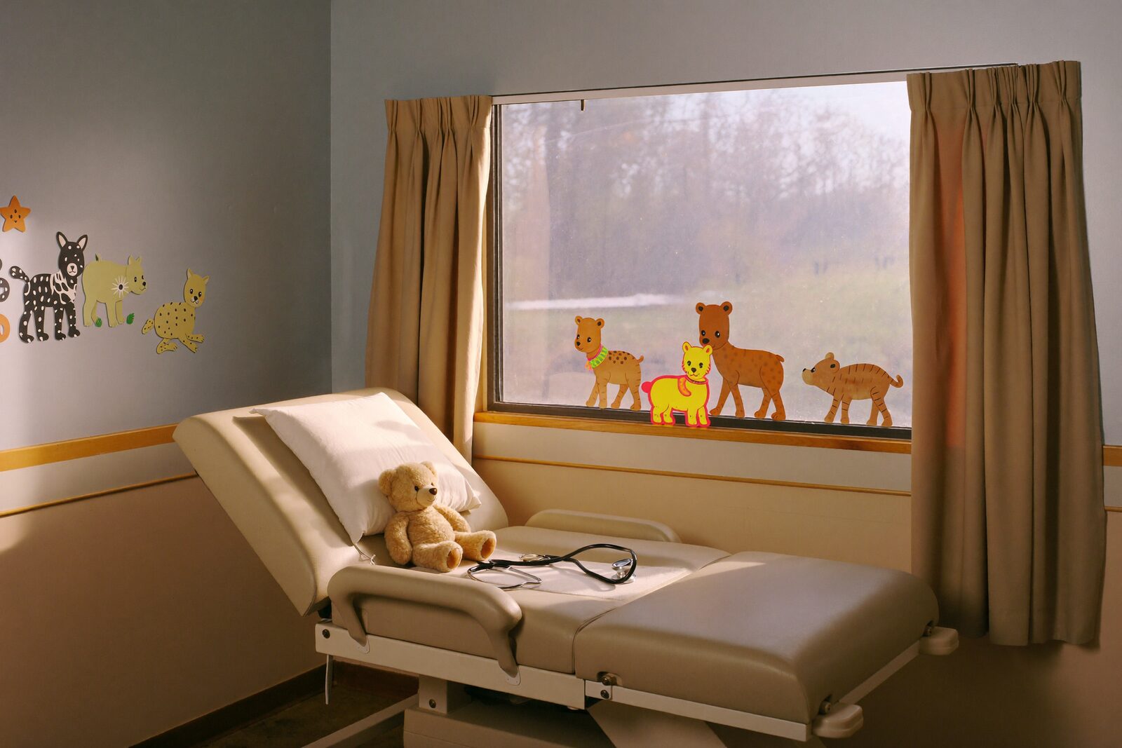 A bright pediatric exam room with a plush bear and stethoscope on the exam table.